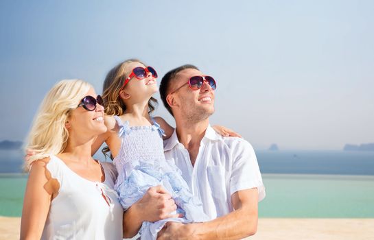 holidays, travel, tourism and people concept - happy family over summer beach background