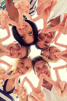 friendship, happiness and people concept - smiling friends in circle showing victory sign