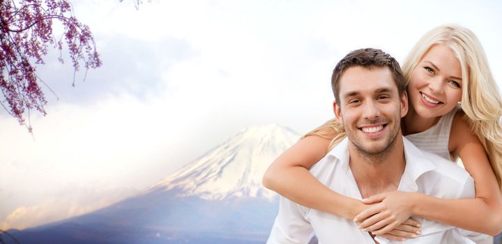 vacation, travel, honeymoon, people and tourism concept - happy couple having fun over fuji mountain background