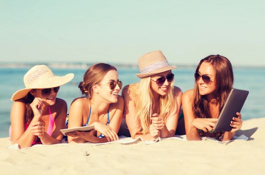 summer vacation, travel, technology and people concept - group of smiling women in sunglasses with tablet pc computers lying on beach