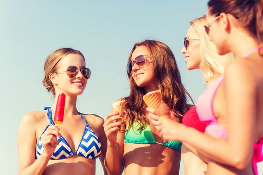 summer vacation, holidays, food, travel and people concept - group of smiling young women eating ice cream on beach