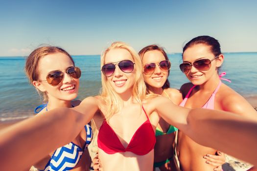 summer vacation, holidays, travel and people concept - group of young smiling women photographing by camera or smartphone on beach