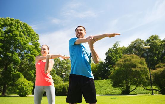 fitness, sport, training and lifestyle concept - smiling couple stretching outdoors