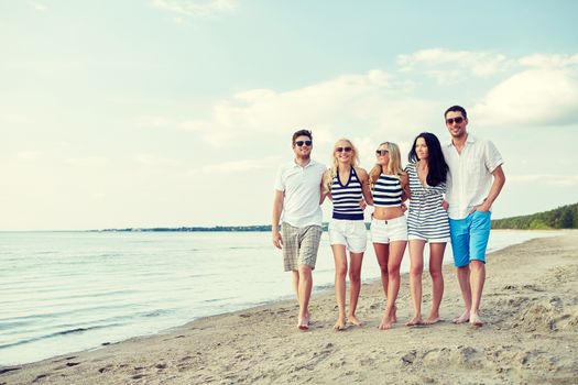 summer, holidays, sea, tourism and people concept - group of smiling friends in sunglasses walking on beach