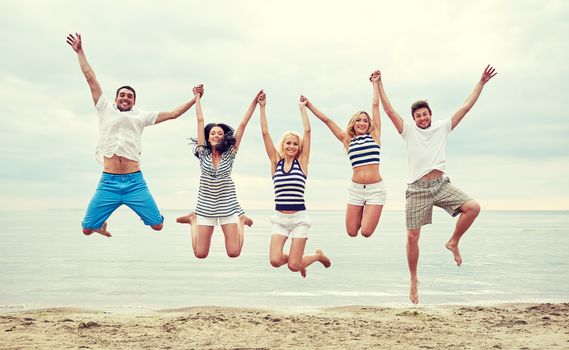 summer, holidays, sea, tourism and people concept - group of smiling friends in sunglasses walking on beach