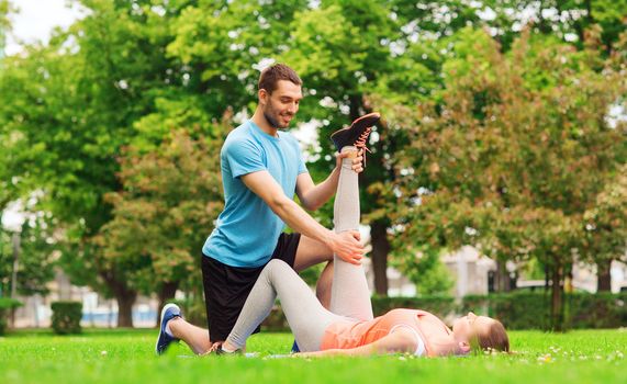 fitness, sport, training and lifestyle concept - smiling couple stretching outdoors