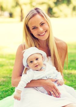 family, child and parenthood concept - happy mother with little baby sitting on blanket in park