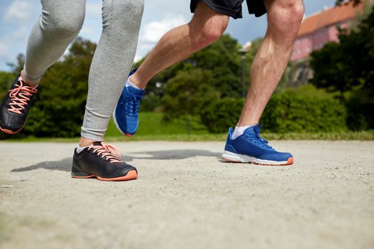 fitness, sport, friendship, people and lifestyle concept - close up of couple running outdoors