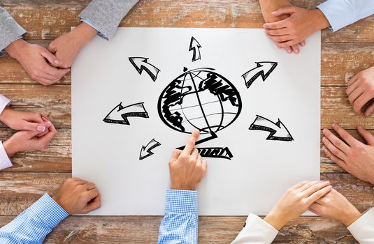 global business, people and team work concept - close up of creative team sitting at table and pointing finger to globe picture on paper in office