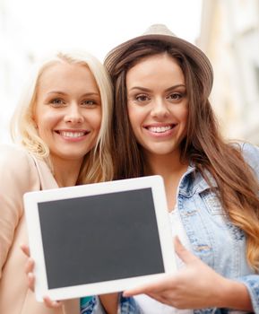 holidays, advertisement, technology and tourism concept - two beautiful girls toursits with blank screen tablet pc in the city