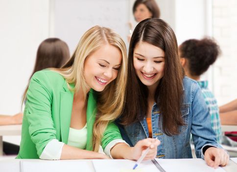 education concept - student girls pointing at notebook at school