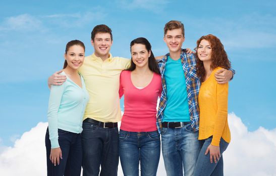 friendship, dream and people concept - group of smiling teenagers standing and hugging over blue sky with white cloud background