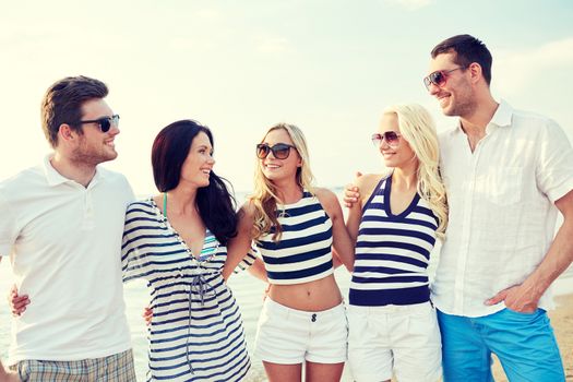 summer, holidays, sea, tourism and people concept - group of smiling friends in sunglasses talking on beach