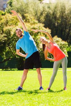 fitness, sport, training and lifestyle concept - smiling couple stretching outdoors