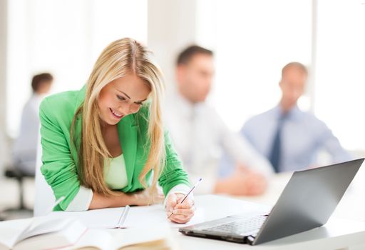 business concept - attractive businesswoman taking notes in office