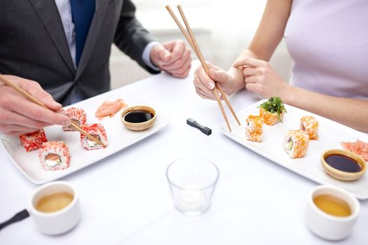 restaurant, food, people, date and holiday concept - close up of couple eating sushi at restaurant