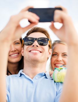 summer holidays, vacation, happy people concept - group of friends taking selfie with cell phone on the beach