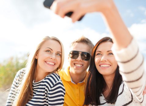 summer holidays, vacation, happy people concept - group of friends taking selfie with cell phone on the beach