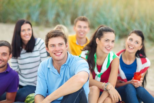 summer holidays, vacation, tourism, travel and people concept - group of happy friends sitting on beach