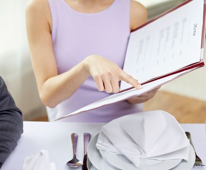 restaurant, food, eating and holiday concept - close up of happy couple with menu choosing dishes at restaurant