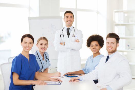 hospital, profession, medical education, people and medicine concept - group of happy doctors meeting on presentation or conference at hospital