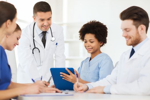 hospital, profession, people and medicine concept - group of happy doctors with tablet pc computers meeting at medical office