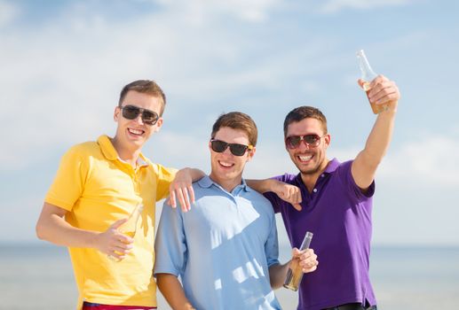 summer holidays, vacation, people and bachelor party concept - group of happy male friends having fun and drinking beer on beach