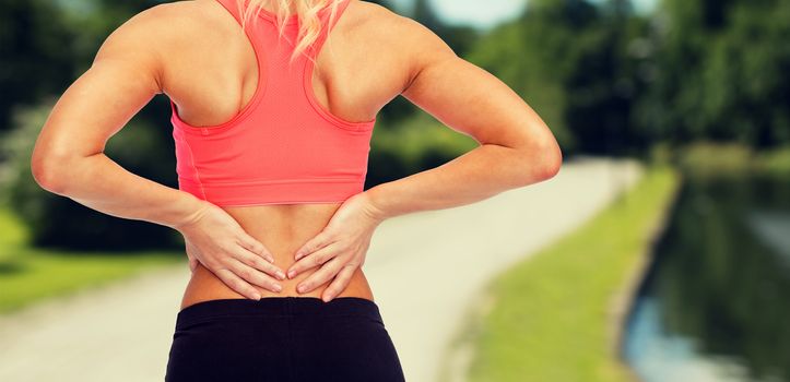 fitness, healthcare and medicine concept - close up of sporty woman touching her back