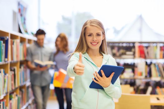 people, education, technology, gesture and school concept - happy student girl or woman with tablet pc computer showing thumbs up in library