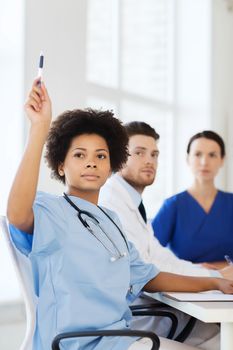 hospital, profession, people and medicine concept - group of happy doctors meeting and asking questions on conference at hospital