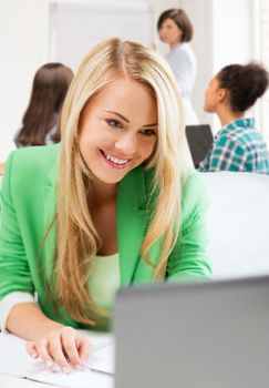 education and internet concept - student girl with laptop in college