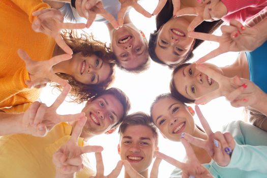 friendship, youth, gesture and people - group of smiling teenagers in circle showing victory sign