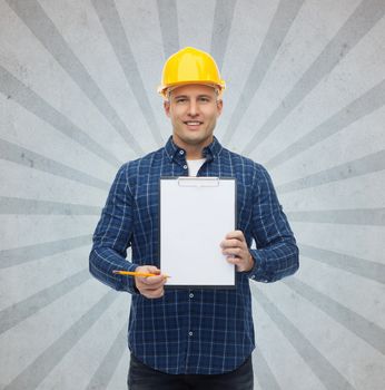repair, construction, building, people and maintenance concept - smiling male builder or manual worker in helmet with clipboard over gray burst rays background