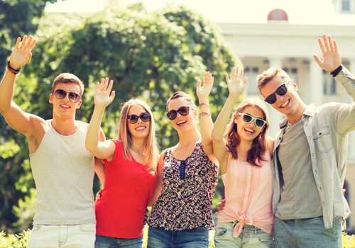 friendship, leisure, summer, gesture and people concept - group of smiling friends waving hands outdoors