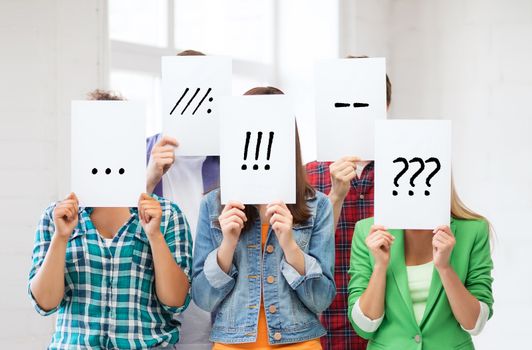 people, emotions and communication concept - group of friends or students covering faces with paper sheets