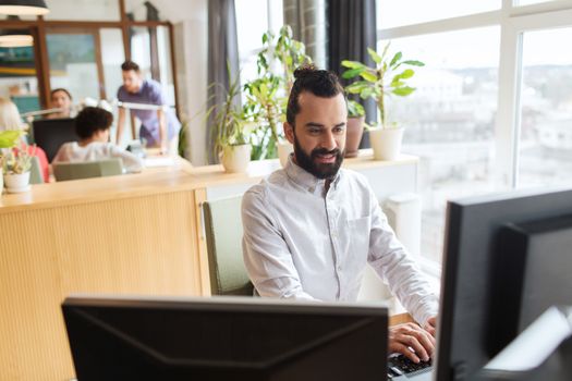 business, startup and people concept - happy businessman or creative male office worker with computer