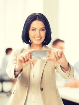 business and bank concept - smiling businesswoman showing credit card in office