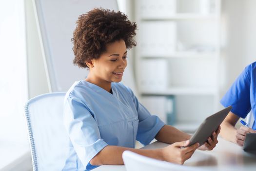 medicine, people and healthcare concept - happy female doctor or nurse with tablet pc computer at hospital