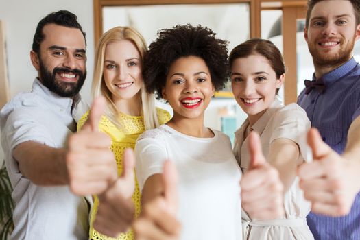 business, startup, people and teamwork concept - happy creative team showing thumbs up in office