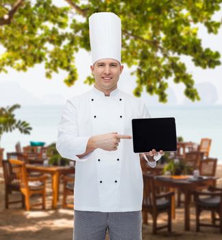 cooking, profession and people concept - happy male chef cook showing tablet pc computer black blank screen over restaurant lounge on beach