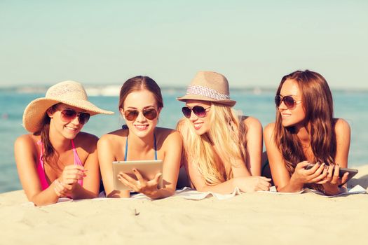 summer vacation, travel, technology and people concept - group of smiling women in sunglasses with tablet pc computers lying on beach