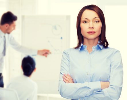 business and education concept - friendly young businesswoman with crossed arms at office