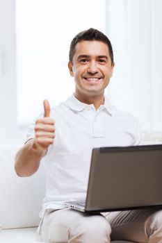 technology, people lifestyle and networking concept - happy man with laptop computer showing thumbs up at home