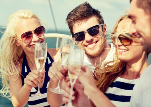 vacation, travel, sea, friendship and people concept - smiling friends with glasses of champagne on yacht