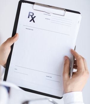 close up of male doctor writing prescription paper