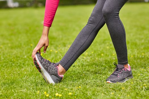 fitness, sport, training, people and lifestyle concept - close up of woman stretching leg in park