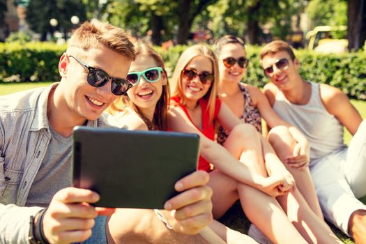 friendship, leisure, summer, technology and people concept - group of smiling friends with tablet pc computer making selfie in park