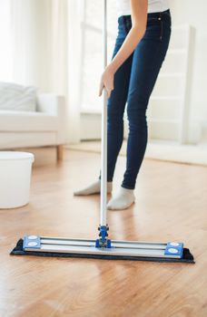 people, housework and housekeeping concept - close up of woman legs with mop cleaning floor at home