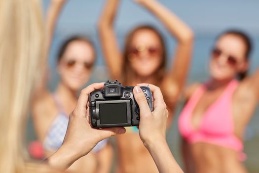 summer vacation, gesture, technology, travel and people concept - close up of smiling young women photographing by camera and waving hands on beach