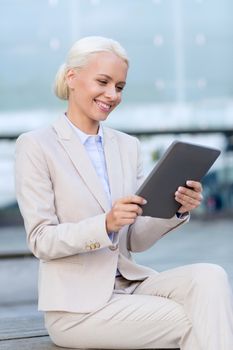 business, education, technology and people concept - smiling businesswoman working with tablet pc computer on city street